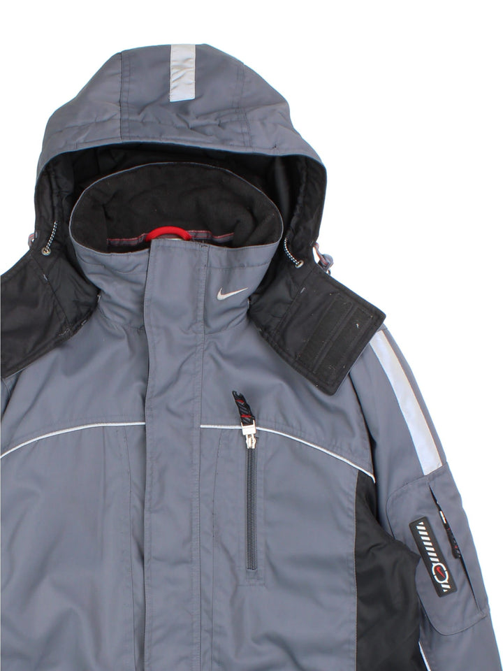 Vintage Nike Y2K Tech Coat in a grey colourway. Zips up and has multiple pockets, insulated with a fleece lining, detachable hood, and has the swoosh logo embroidered on the front and back.