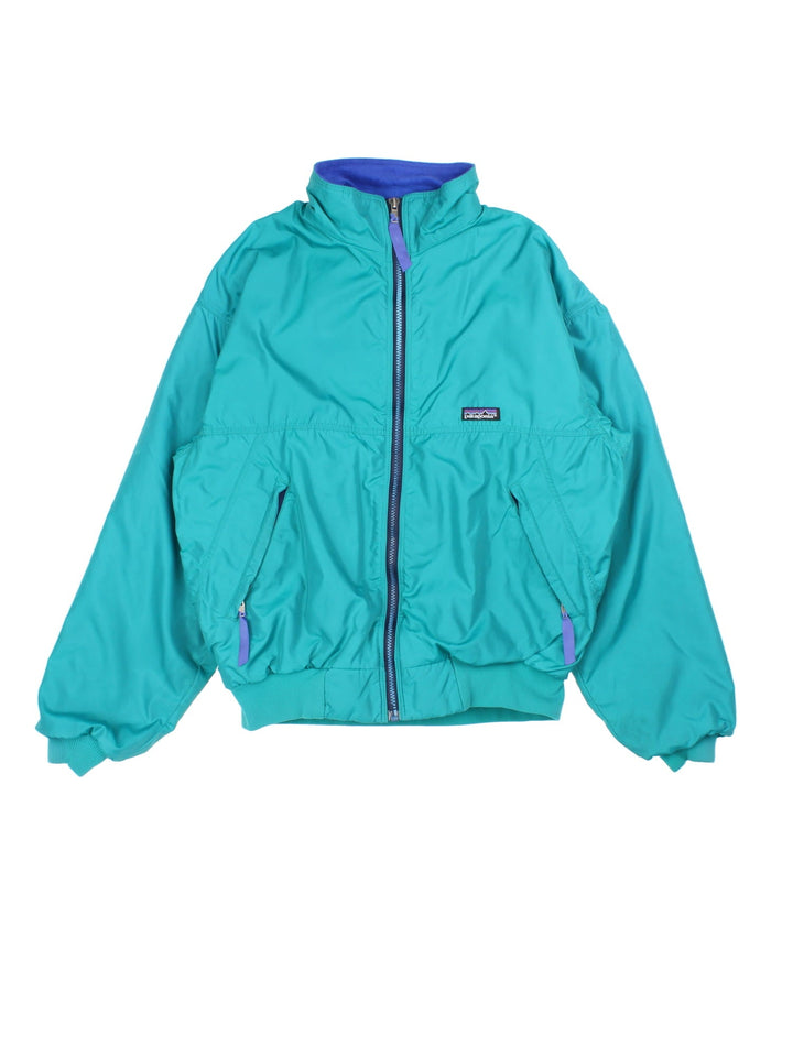 Vintage 90's Patagonia Bomber Jacket in a turquoise blue colourway. Zips up and has side pockets, insulated with a fleece lining, and has the logo embroidered on the front.