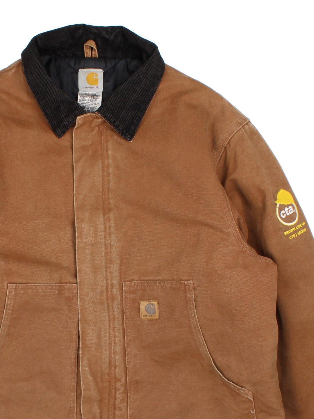 Carhartt Arctic Jacket in a brown colourway with full zip and double pocket on the front. Suede collar, Carhartt classic logo on the front pocket and a logo on the sleeve.