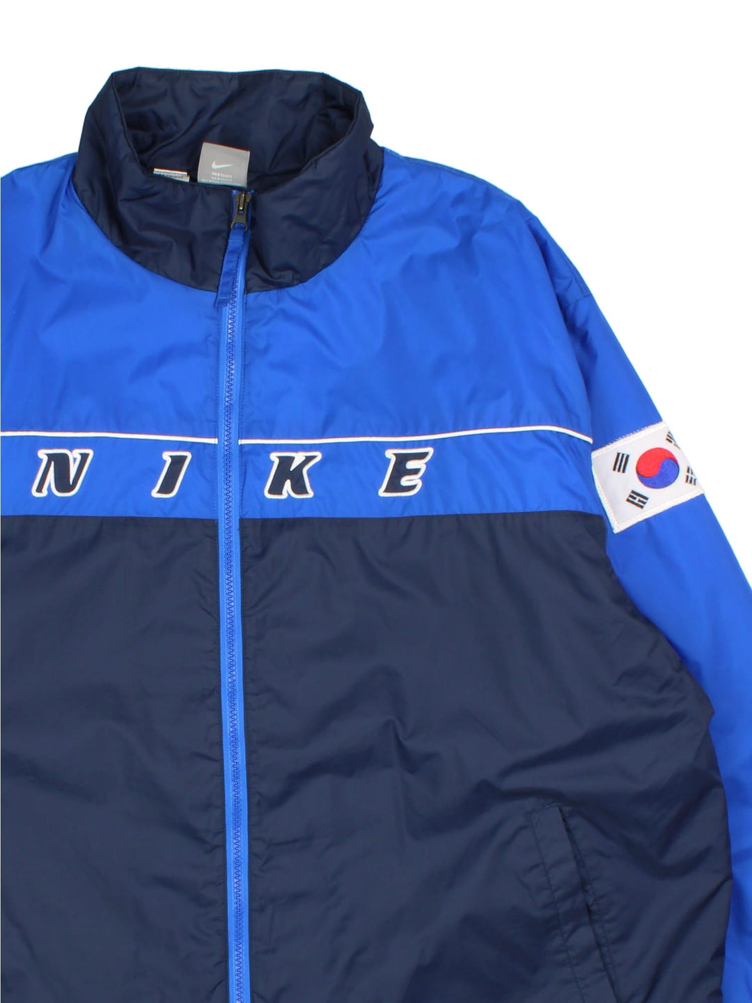 Vintage Nike Korea Coach Jacket in a blue colourway. Zips up and has side pockets, insulated with a quilted lining, and the logo embroidered on the front and on the back Korea spell out with embroidered tiger graphic.