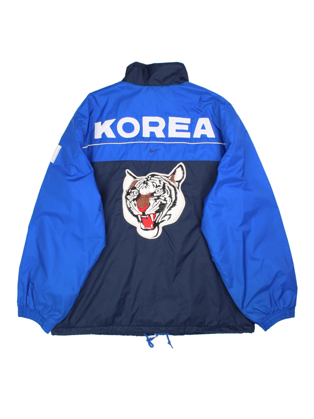 Vintage Nike Korea Coach Jacket in a blue colourway. Zips up and has side pockets, insulated with a quilted lining, and the logo embroidered on the front and on the back Korea spell out with embroidered tiger graphic.