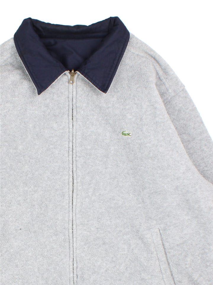 Lacoste Reversible Bomber Jacket in a blue and grey colourway with either jacket or fleece reversible options. Zips up and has side pockets, insulated lining, and has the logo embroidered on the front.