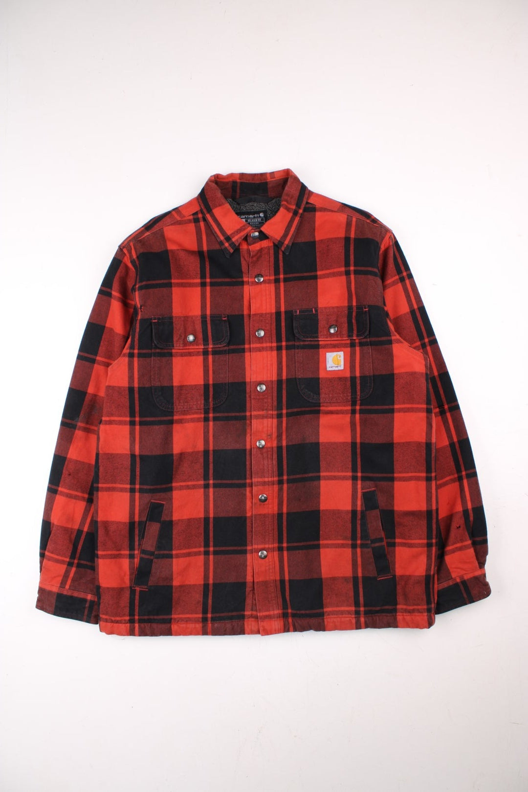 Carhartt Flannel Shirt Jacket in a red and black plaid colourway. Buttons up and has double chest pockets, insulated with a sherpa lining, and has the logo embroidered on the front.