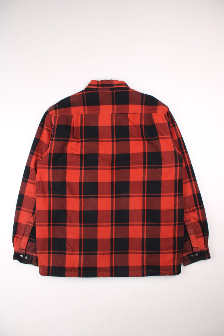 Carhartt Flannel Shirt Jacket in a red and black plaid colourway. Buttons up and has double chest pockets, insulated with a sherpa lining, and has the logo embroidered on the front.