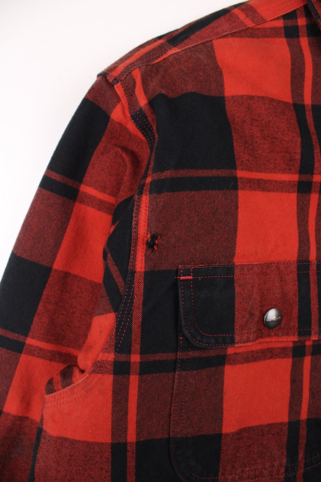 Carhartt Flannel Shirt Jacket in a red and black plaid colourway. Buttons up and has double chest pockets, insulated with a sherpa lining, and has the logo embroidered on the front.