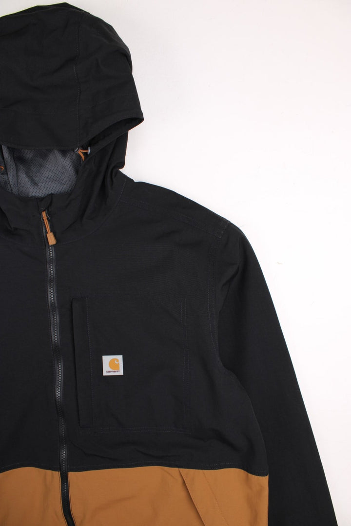 Carhartt Storm Defender Jacket in a black and brown colourway. Zips up and has multiple pockets, mesh lining, hooded and has the logo embroidered on the front.