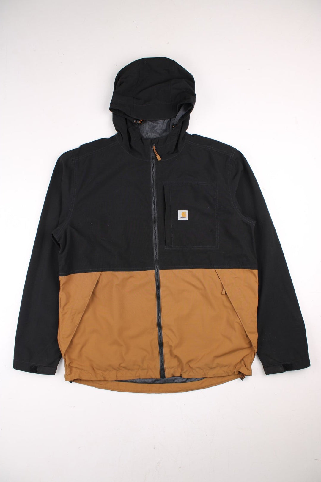 Carhartt Storm Defender Jacket in a black and brown colourway. Zips up and has multiple pockets, mesh lining, hooded and has the logo embroidered on the front.