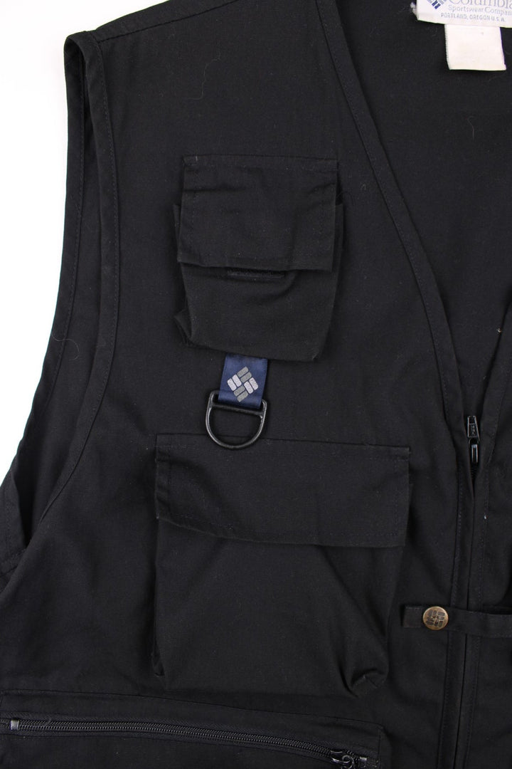 Vintage Columbia PFG Fishing Vest Gilet in a black colourway. Zips up and has multiple utility pockets, and has the logo embroidered on the back.