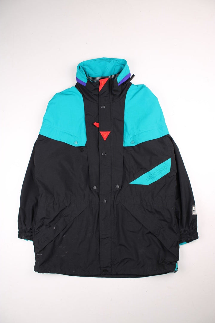 Vintage Helly Hansen Equipe Jacket in a black and blue colourway. Zip and buttons up, has multiple pockets, mesh lining, and has the logos embroidered on the front and left sleeve.