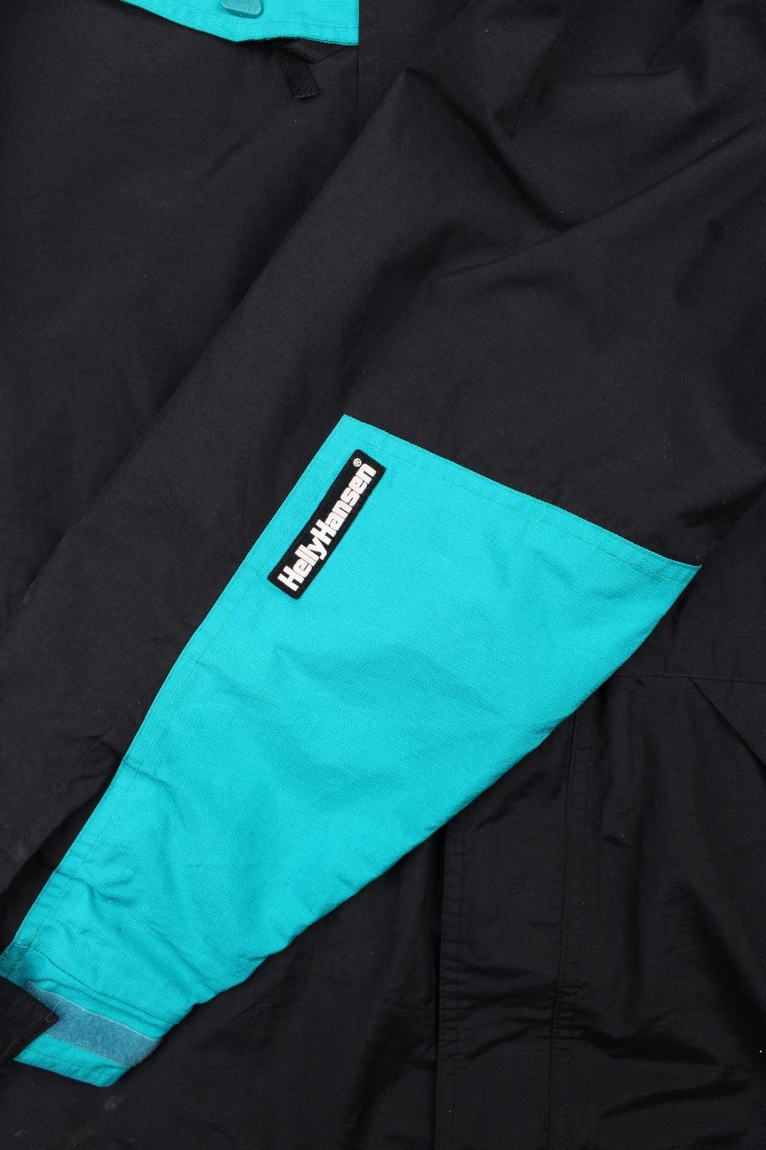 Vintage Helly Hansen Equipe Jacket in a black and blue colourway. Zip and buttons up, has multiple pockets, mesh lining, and has the logos embroidered on the front and left sleeve.