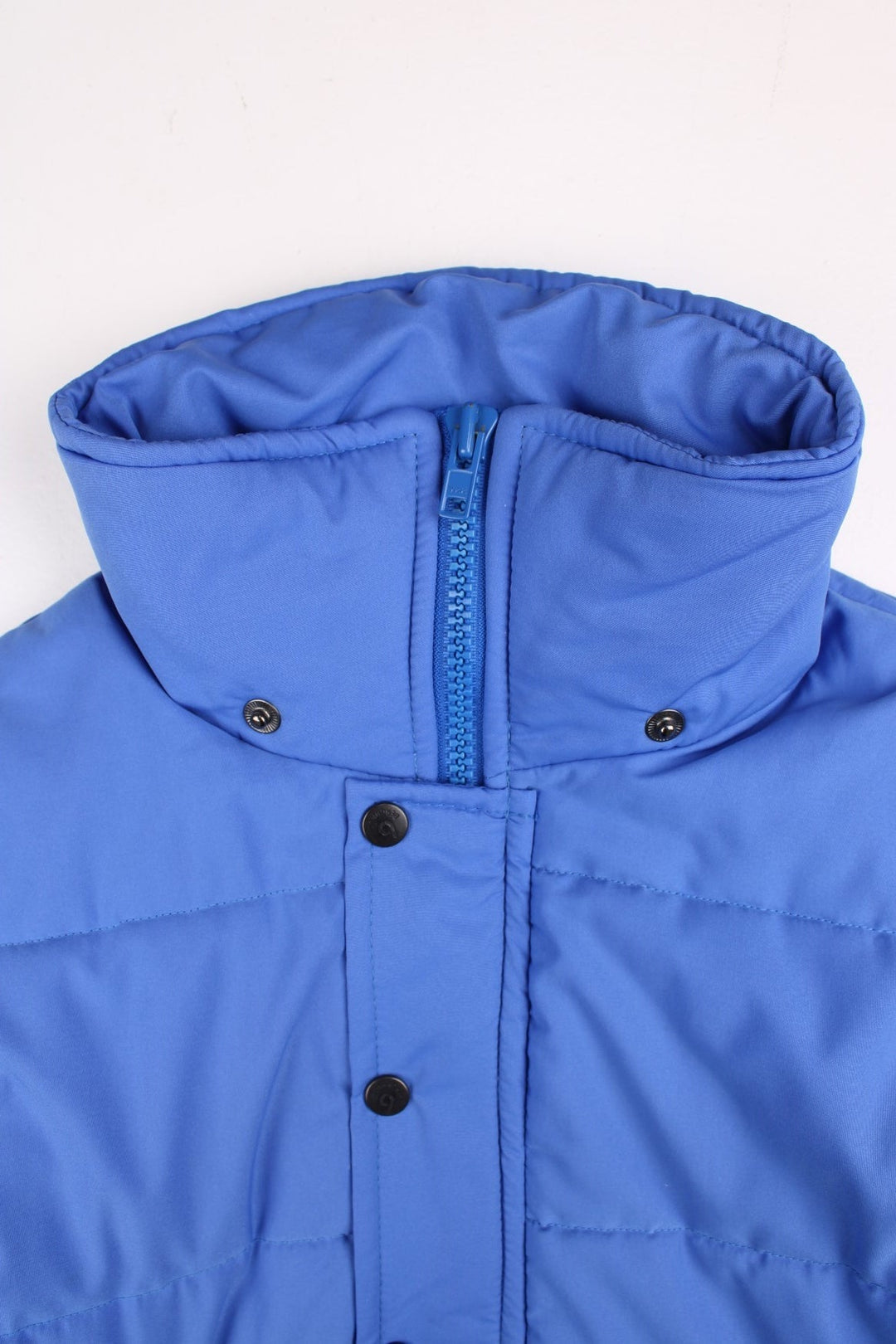 Vintage Berghaus Ice Cap Pole Puffer Jacket in a blue and pink colourway. Zip and buttons up, has side pockets, detachable hood, insulated, and has the logo embroidered on the front.