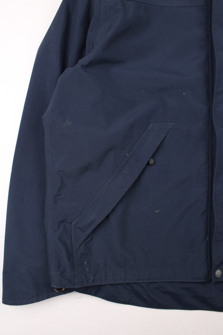 Carhartt Shoreline Jacket in a navy blue colourway. Zips up and has multiple pockets, detachable hood, mesh lining, and has the logo embroidered on the front.