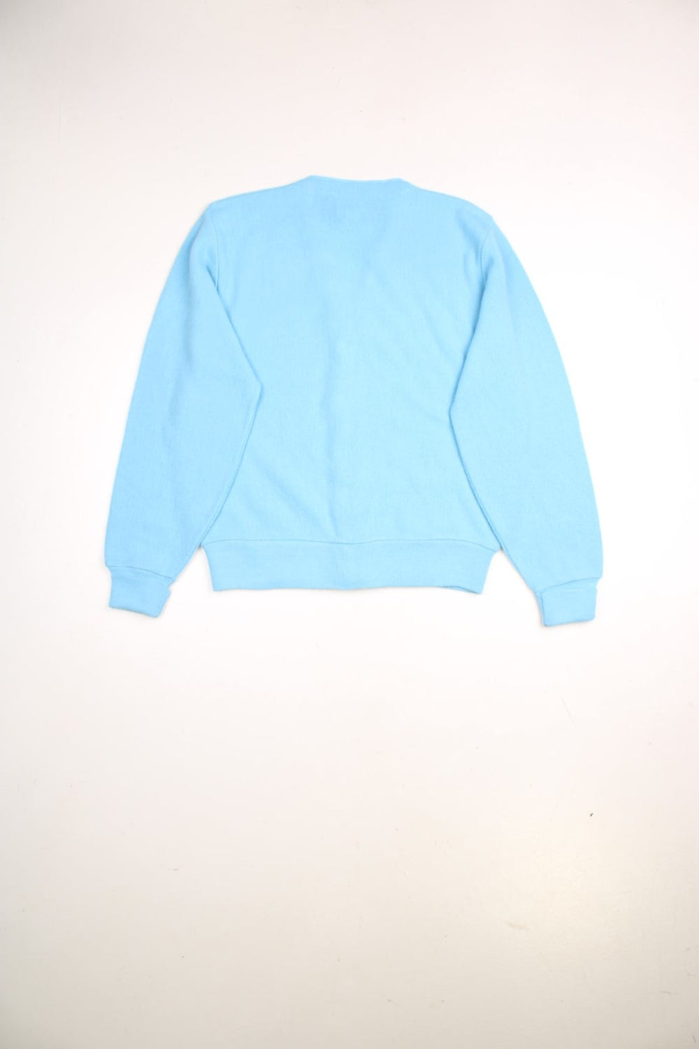 Lacoste jumper in a light blue colourway with the Lacoste logo stitched on the front. The cardigan closes with grey and silver buttons, and has folded cuffs. Made in USA. 