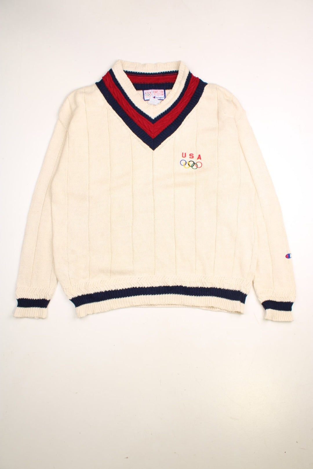 Champion USA Olympics Team jumper in a tan colourway. The jumper has a deep V neck, similar to a cricket jumper, with navy and burgundy trim around the neckline and hem.The USA team logo is embroidered on the front. Made in the USA. 