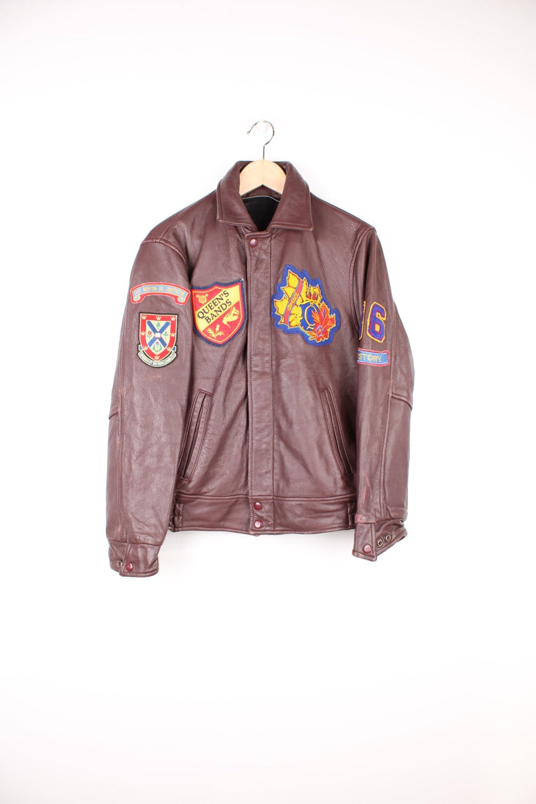 Vintage 80's Queen's University Canada Leather Varsity Jacket in a brown colourway, zip and button up, side pockets, and has the university logo and badges embroidered on throughout. 