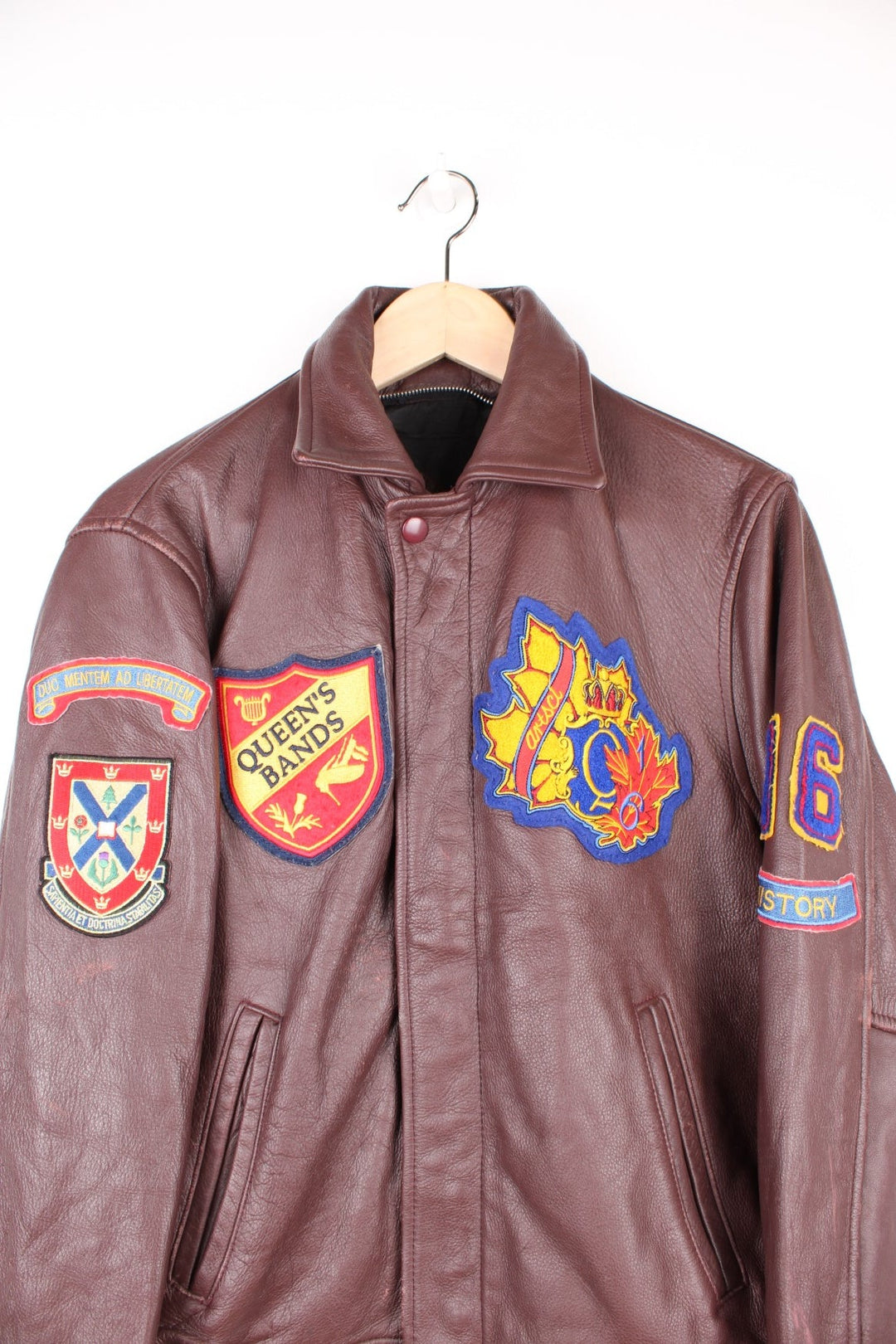 Vintage 80's Queen's University Canada Leather Varsity Jacket in a brown colourway, zip and button up, side pockets, and has the university logo and badges embroidered on throughout. 