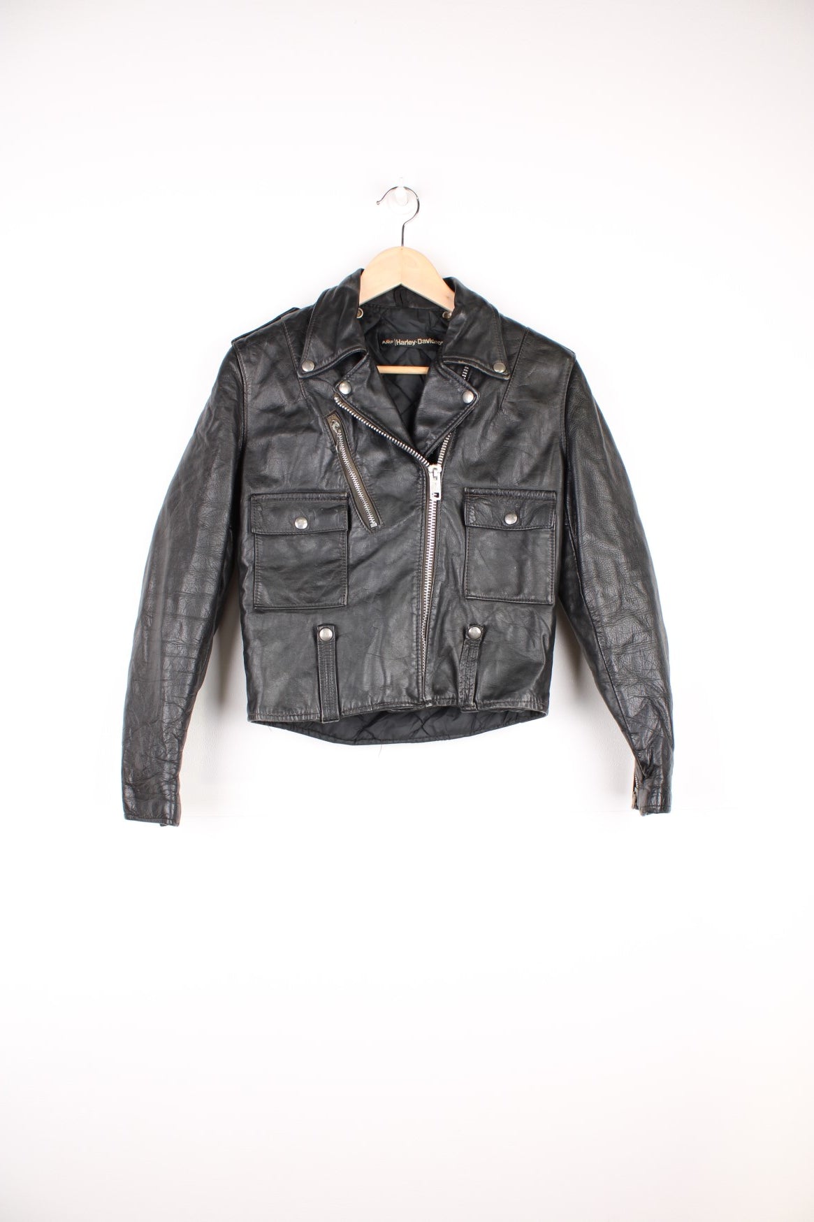 Vintage Harley Davidson Leather Biker Jacket in a black colourway, zip up with multiple pockets, insulated with a quilted lining, and has buckles on the front and back.