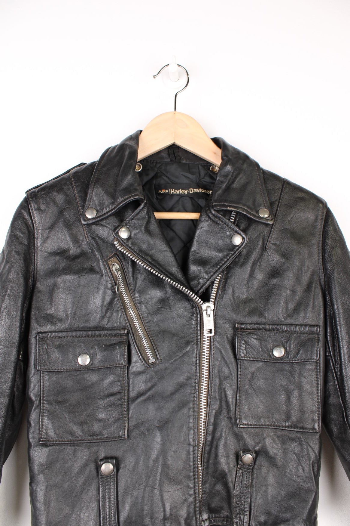 Vintage Harley Davidson Leather Biker Jacket in a black colourway, zip up with multiple pockets, insulated with a quilted lining, and has buckles on the front and back.