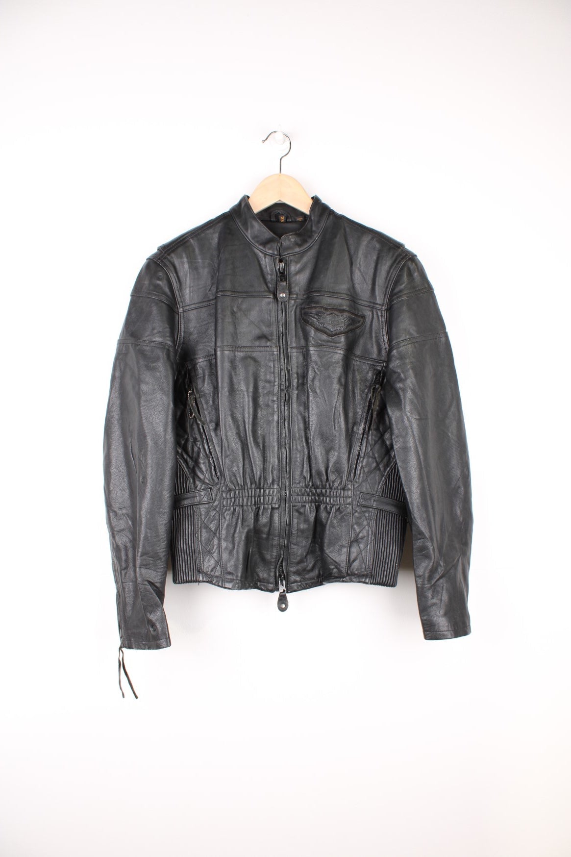 Harley Davidson Motorcycle Jacket in a black colourway, zip up with side pockets, has adjustable waistline buckles, air vent zip on the back, mesh lining, and the logo embroidered on the front and spell out on the back. 