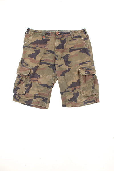 Vintage Alpha Industries Camo Cargo Shorts in a green, black and brown colourway, has an adjustable waist, multiple pockets, and has the logo embroidered on the right pocket.