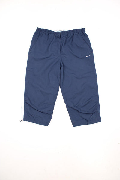 Y2K Nike Quarter Length Shorts in a navy and white colourway with stripes going down either side, has a elasticated waist, pockets and the swoosh logo embroidered on the front. 