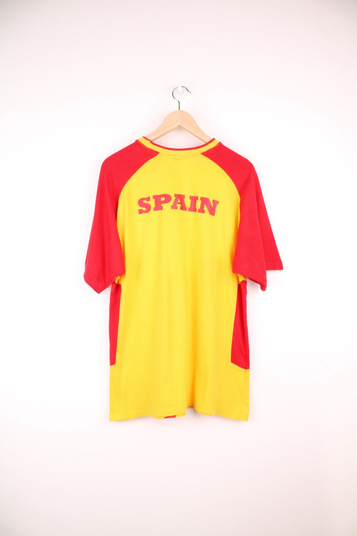 Umbro Spain Football T-Shirt in a yellow and red colourway with the logos printed on the front and on the back is the Spain spell out print.