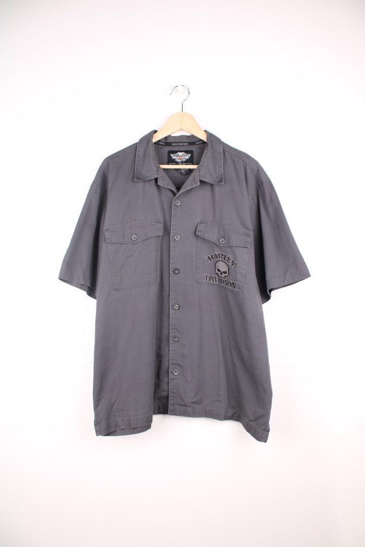 Y2K Harley Davidson Skull Shirt in a grey and black colourway, workwear style, button up with double chest pockets, and has the logo and skull design embroidered on the front and back. 