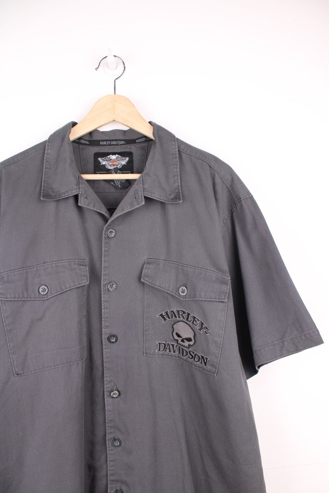 Y2K Harley Davidson Skull Shirt in a grey and black colourway, workwear style, button up with double chest pockets, and has the logo and skull design embroidered on the front and back. 