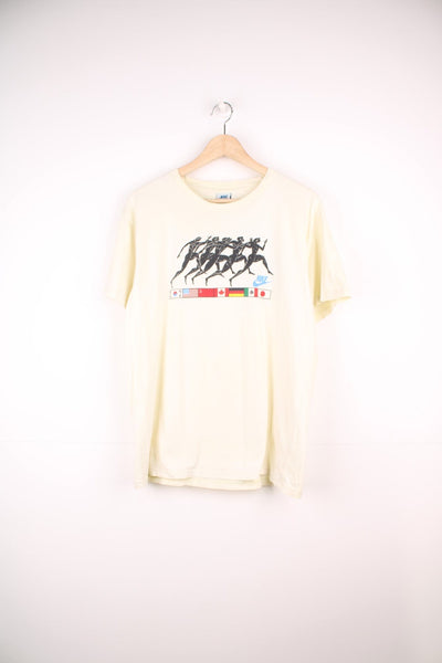 Vintage Nike 1988 Olympic Runners T-Shirt in a pale yellow colourway, has the runners and country flags graphic design printed on the front, as well as the logo and '88' printed on the back. 