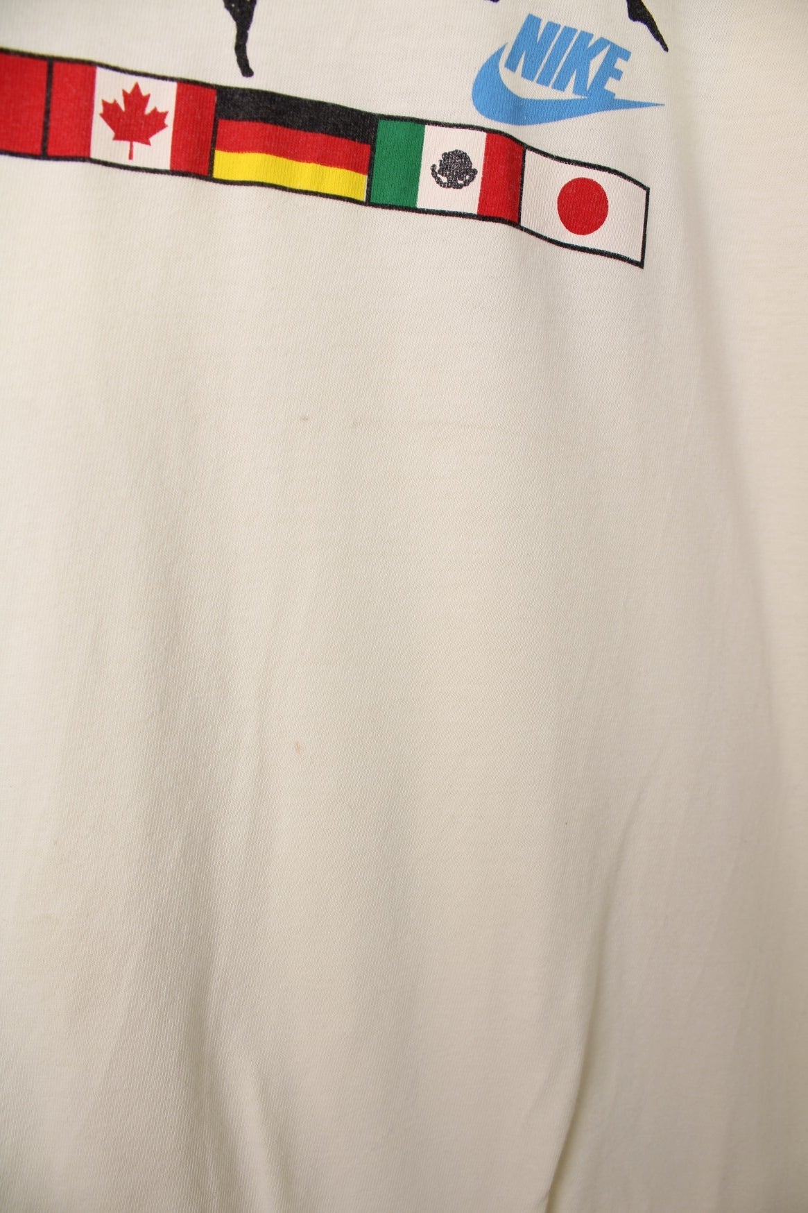 Vintage Nike 1988 Olympic Runners T-Shirt in a pale yellow colourway, has the runners and country flags graphic design printed on the front, as well as the logo and &