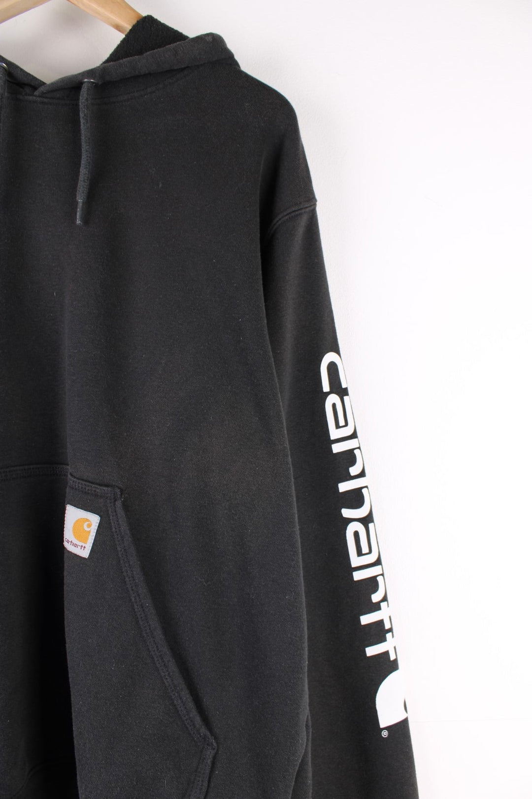 Carhartt Hoodie in a black colourway with the logo embroidered on the front pocket and spell out printed down the left sleeve.