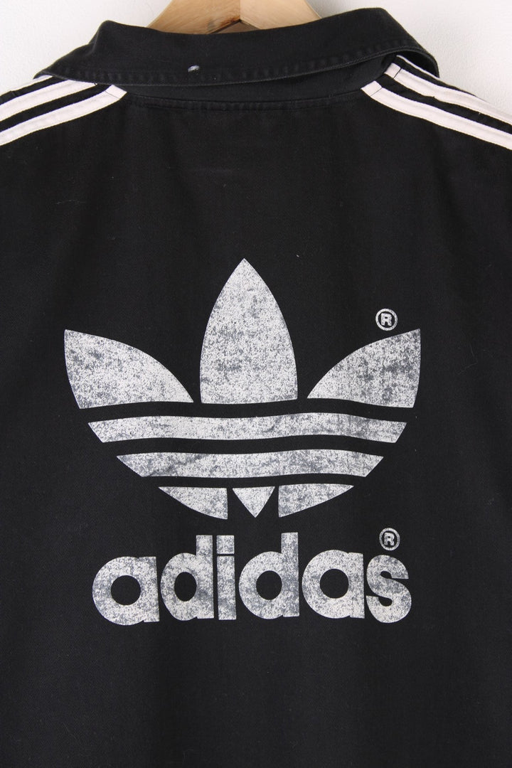 Vintage 90's Adidas Training Top in a black and white colourway, has the iconic three stripes going down the sleeves, and the logo is printed on front and back.