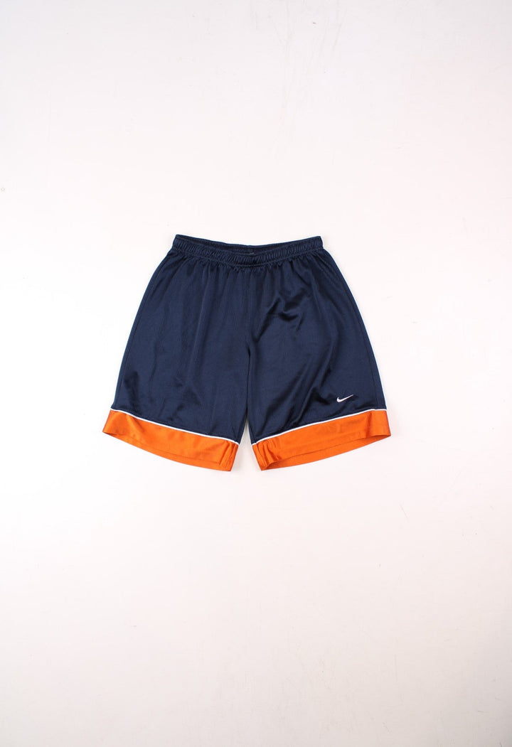 Nike shorts in navy blue and orange with white piping, an elasticated waist, and an embroidered logo on the front.