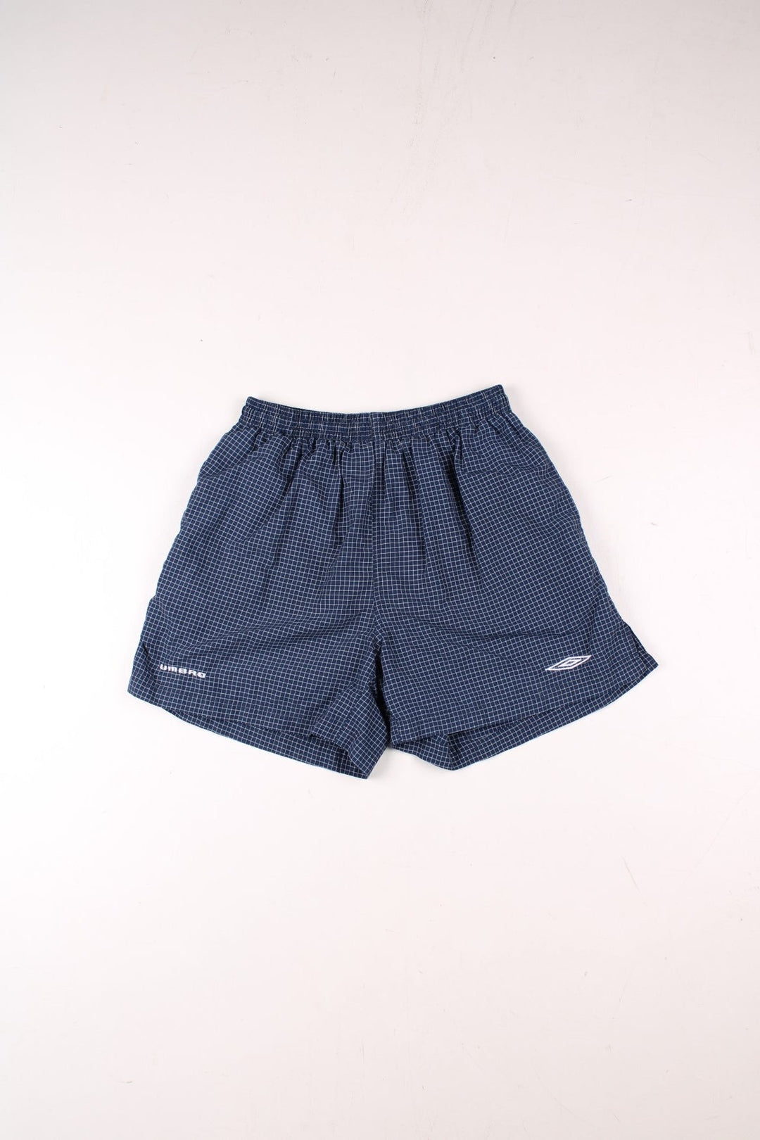 Umbro shorts in navy blue and white check, with an elasticated waist and an embroidered logo.