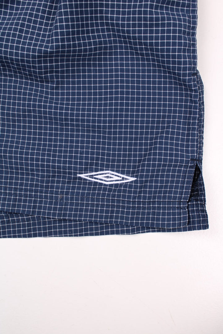 Umbro shorts in navy blue and white check, with an elasticated waist and an embroidered logo.