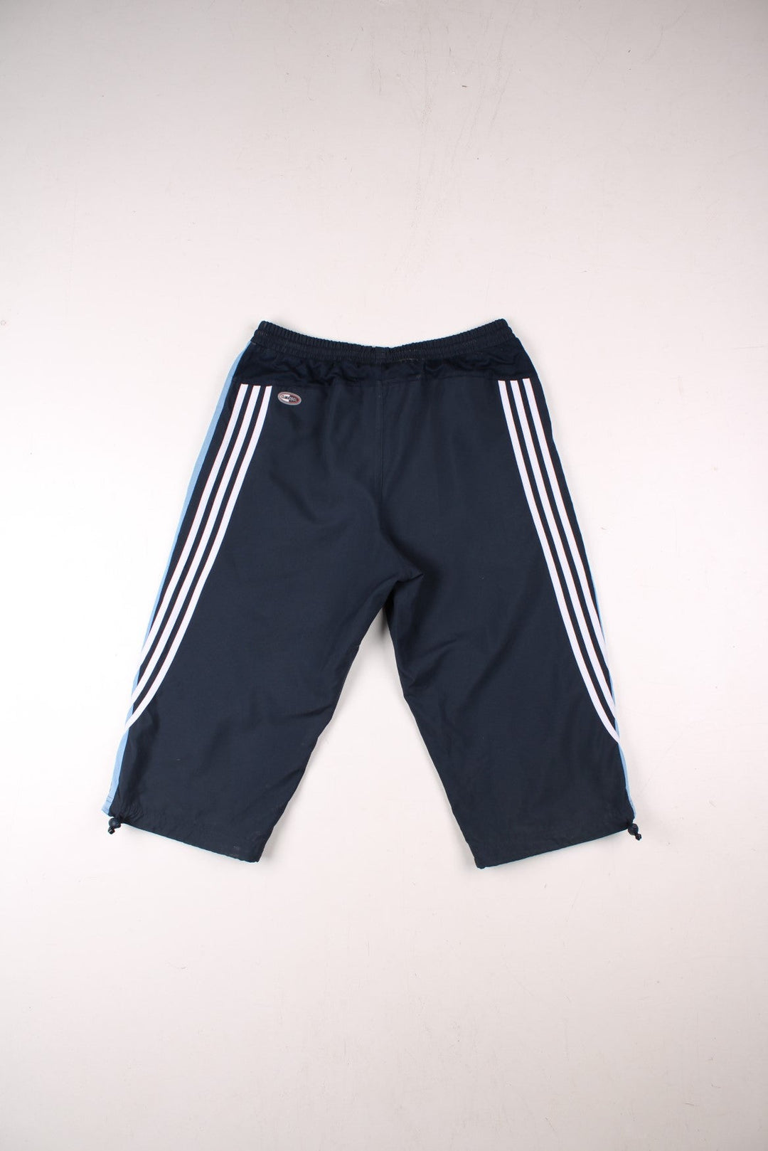 Adidas 3/4 length shorts in navy blue with blue side panels and white three-stripe, an elasticated waist, two zipped pockets and an embroidered logo.