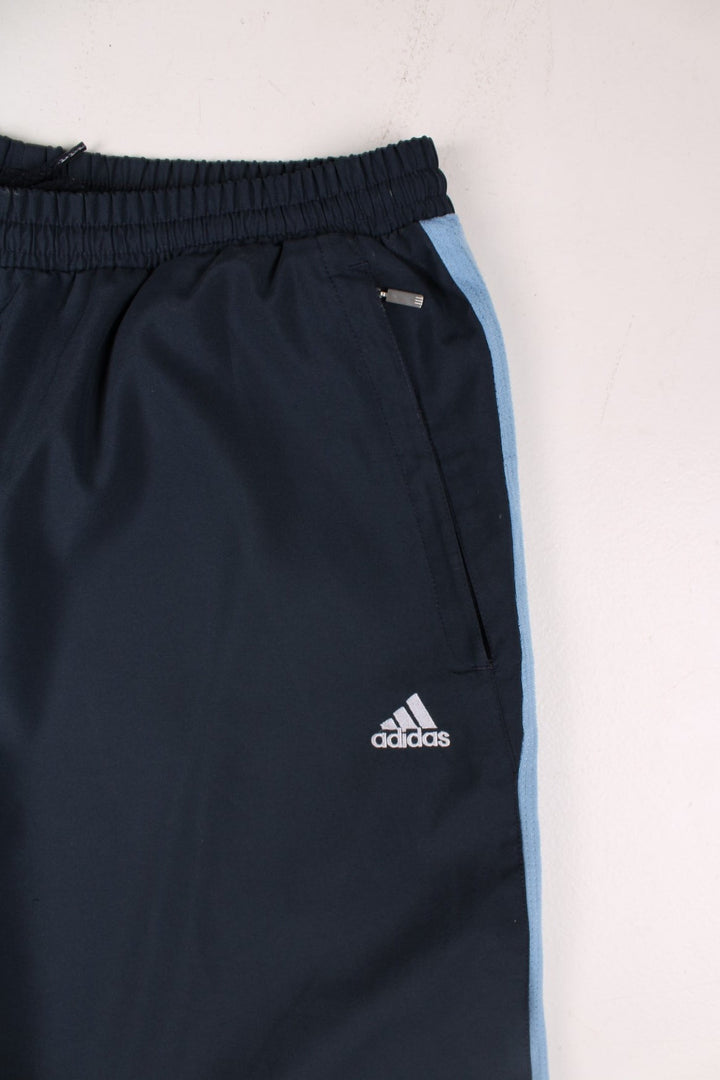 Adidas 3/4 length shorts in navy blue with blue side panels and white three-stripe, an elasticated waist, two zipped pockets and an embroidered logo.