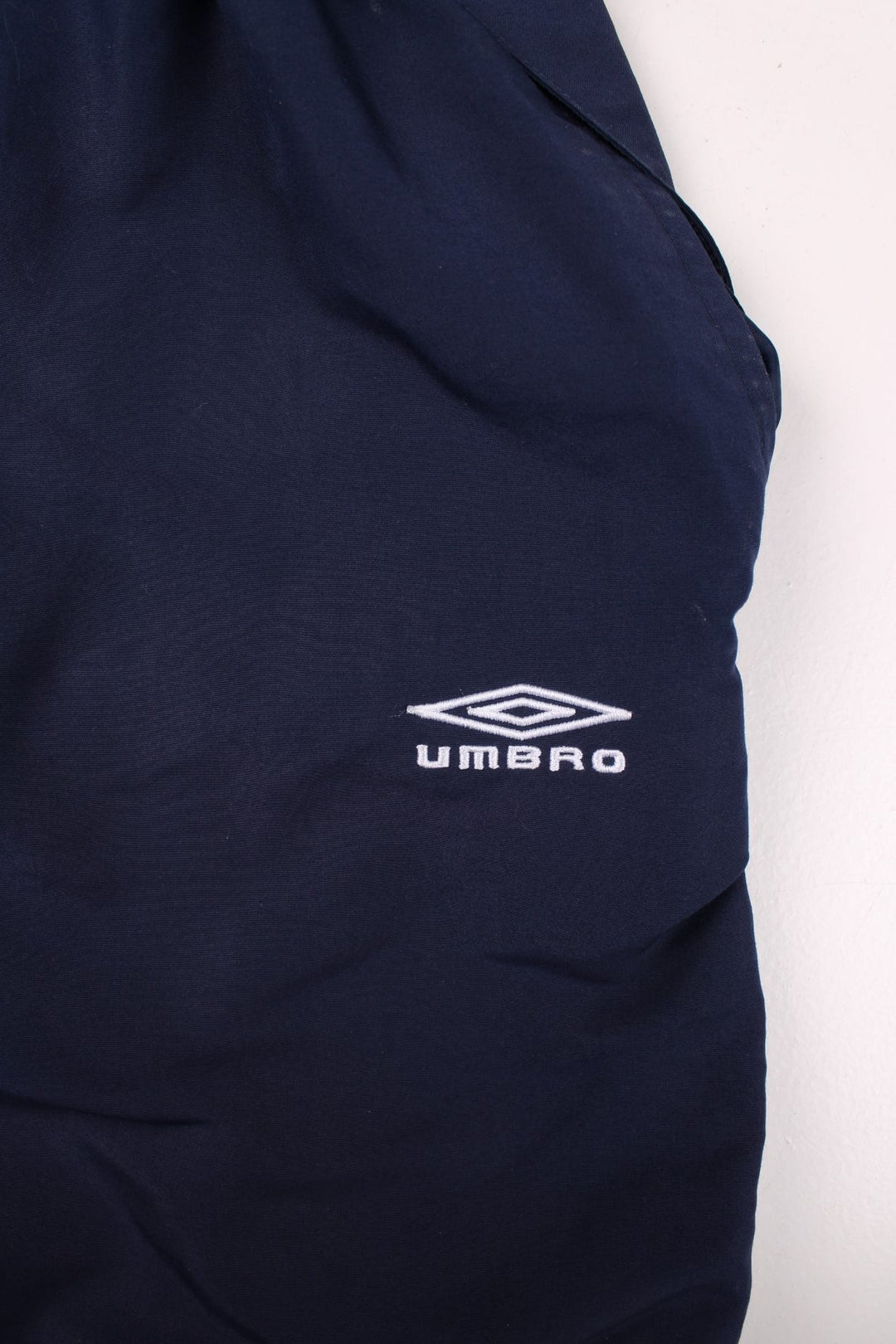 Umbro 3/4 shorts in navy blue with white piping, two pockets, an elasticated waist wirth a drawstring, and an embroidered logo on the front and side.