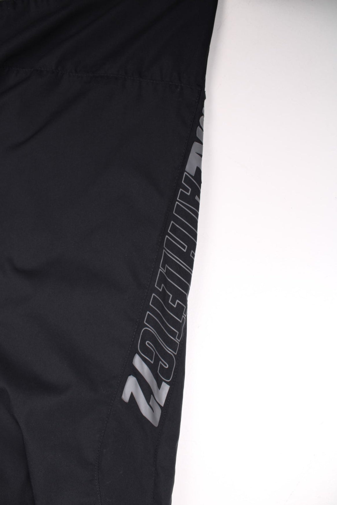 Nike Athletic 72 tracksuit bottoms in black with an elasticated waist, a toggle adjuster, two pockets, a printed spellout up the left leg, and an embroidered logo on the front.