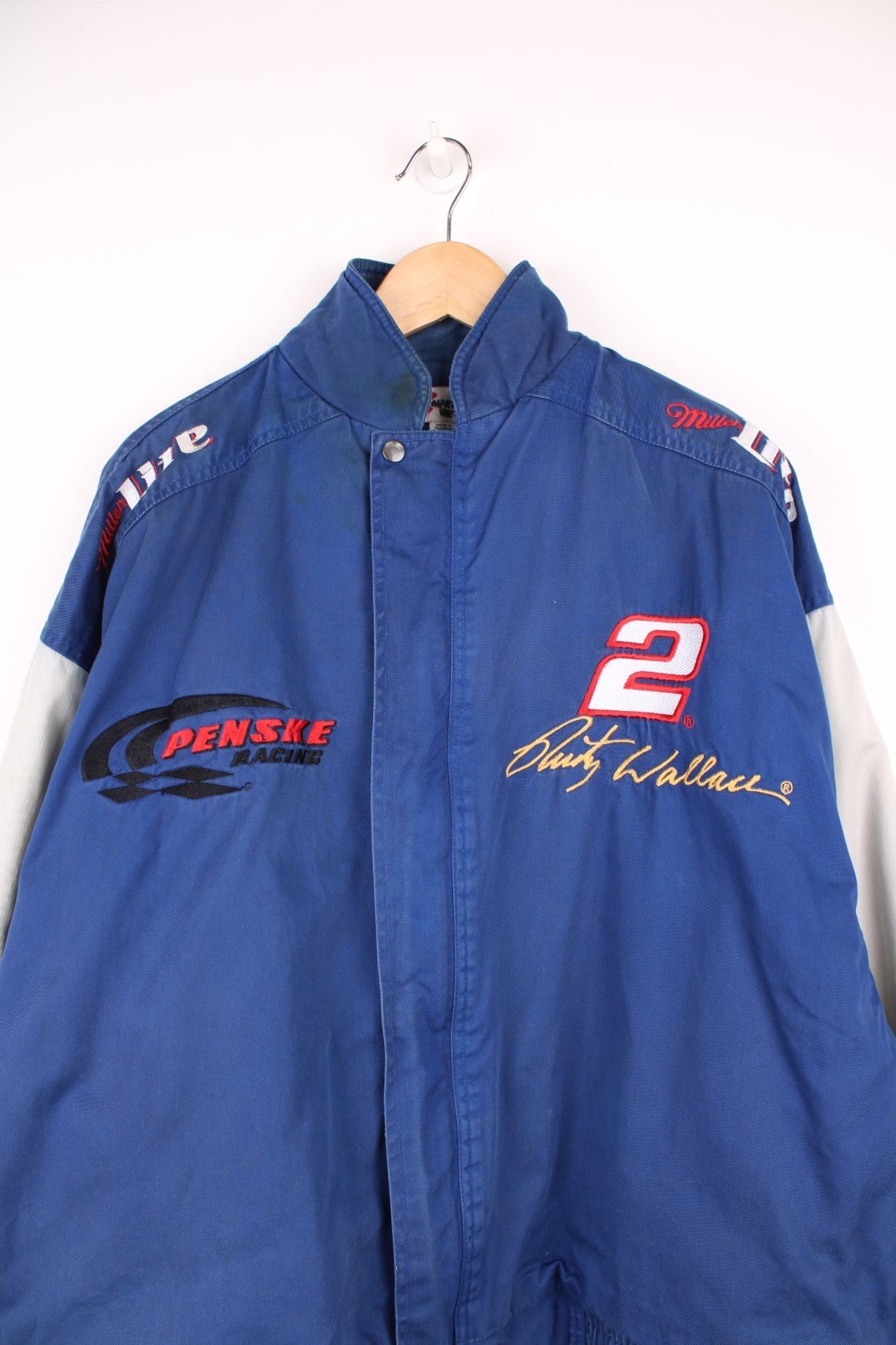 Vintage Rusty Wallace, Penske Racing, zip through NASCAR jacket in blue and grey. Features embroidered sponsor logos, badge on the chest and Rusty Wallace across the back.