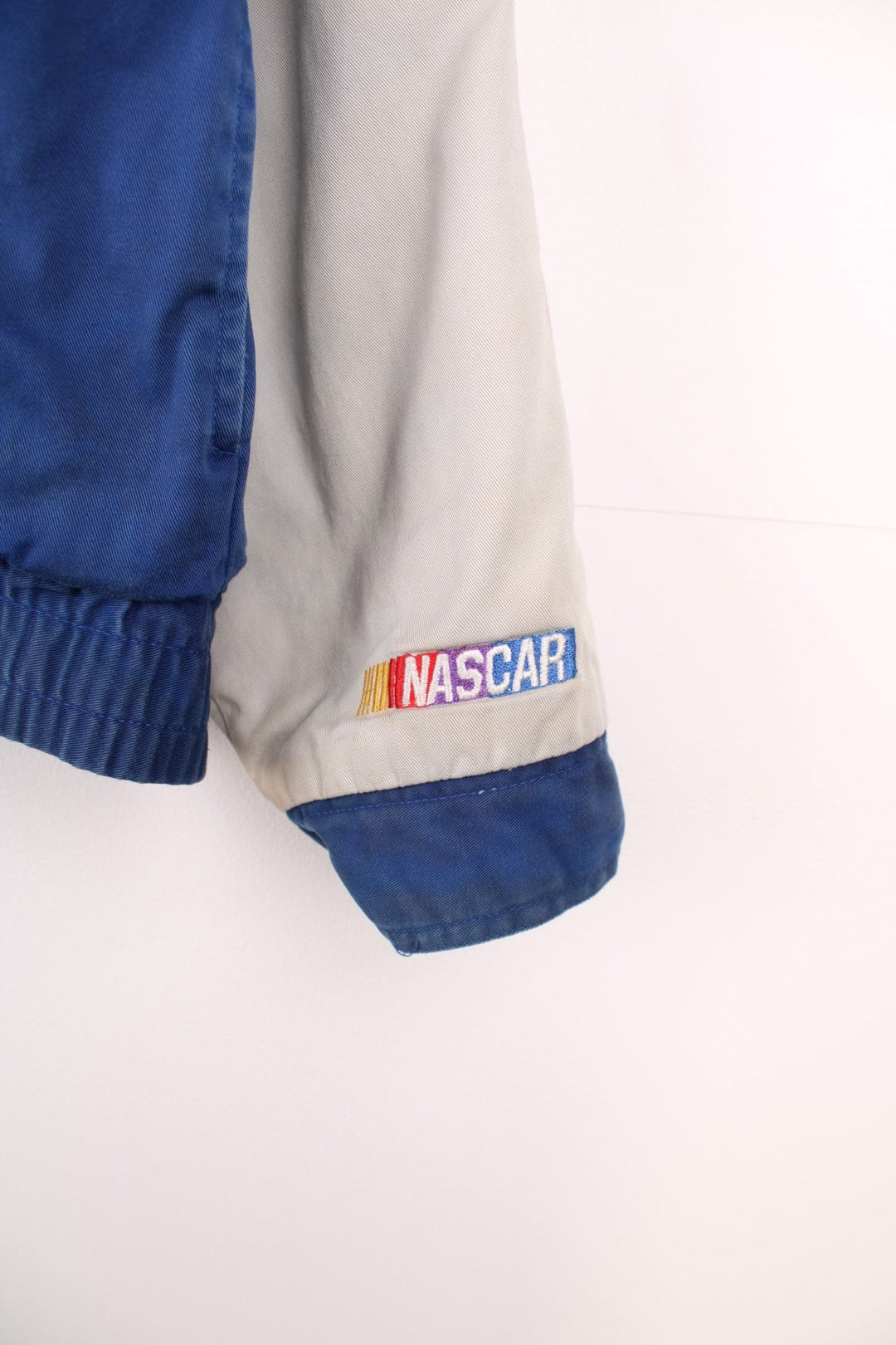 Vintage Rusty Wallace, Penske Racing, zip through NASCAR jacket in blue and grey. Features embroidered sponsor logos, badge on the chest and Rusty Wallace across the back.