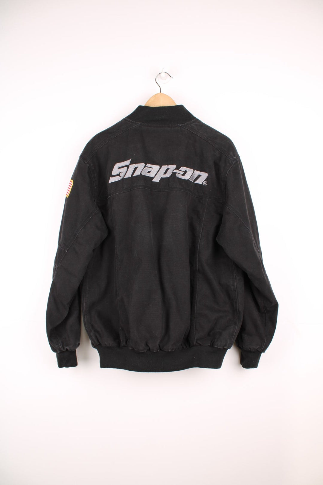 Vintage Snap On Tools zip through canvas bomber jacket with multiple pockets. Features embroidered logo on the chest, USA flag badge on the sleeve, and embossed silver buttons and studs.