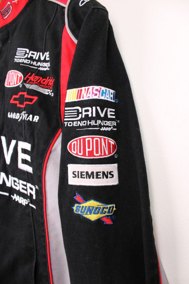 Jeff Gordon Drive To End Hunger NASCAR jacket by Chase Authentics in black, grey and red. Features embroidered sponsor logos on the front and sleeves.