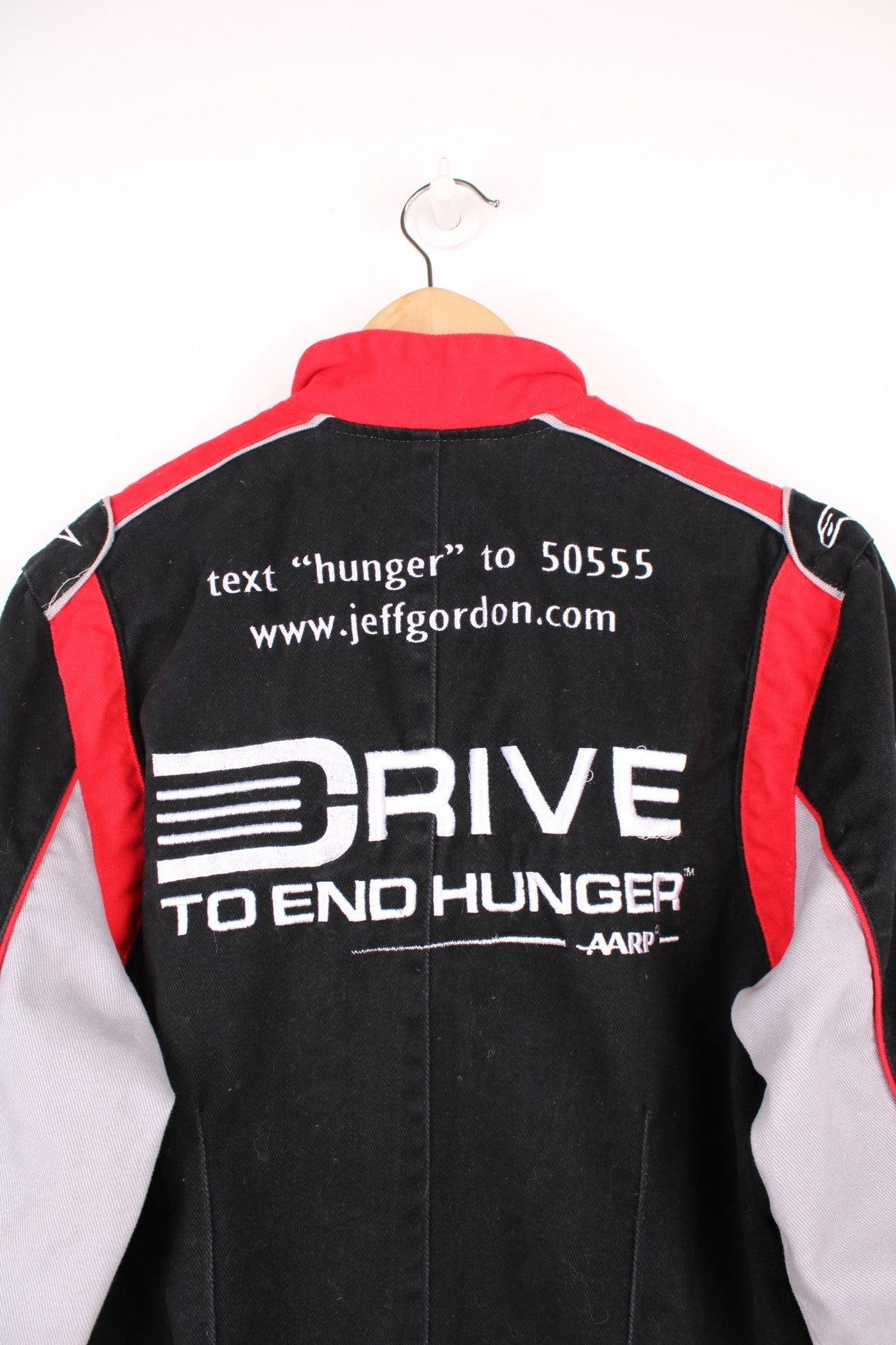 Jeff Gordon Drive To End Hunger NASCAR jacket by Chase Authentics in black, grey and red. Features embroidered sponsor logos on the front and sleeves.