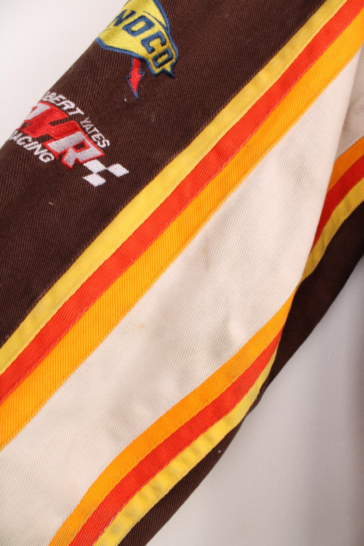 Vintage Dale Jarrett UPS NASCAR jacket by Chase Authentics in brown and orange. Features embroidered sponsor badges all over.  