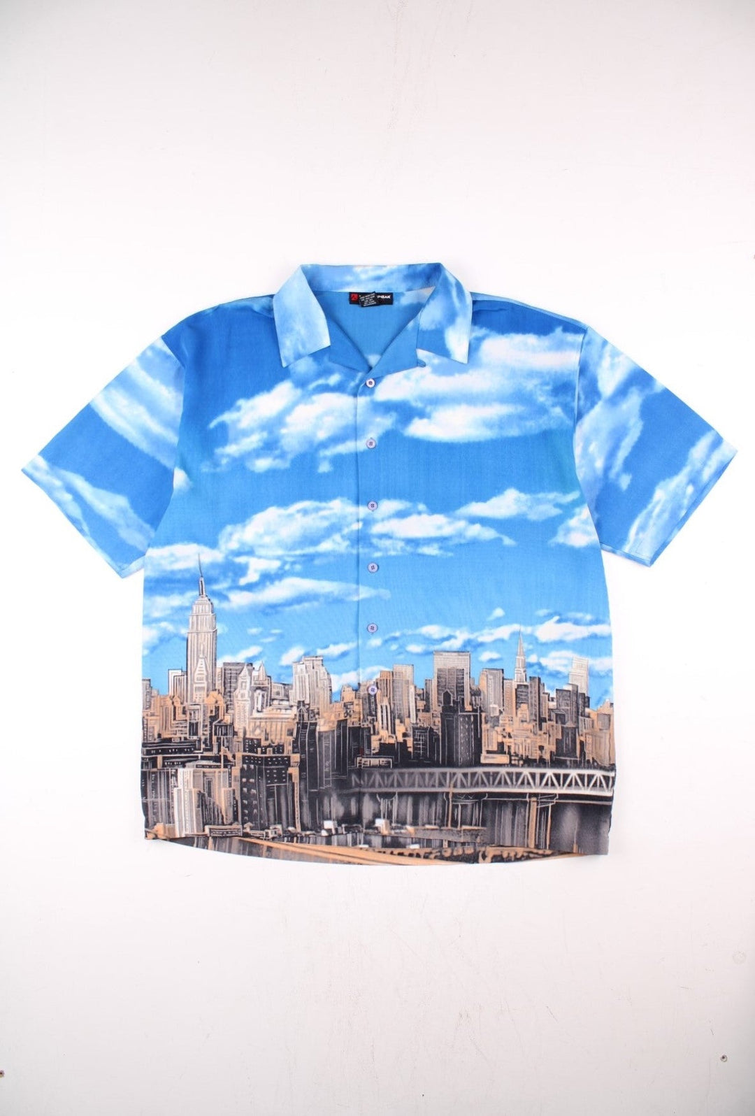 Vintage Northpeak shirt in blue with print of the New York City skyline against a blue sky and clouds.