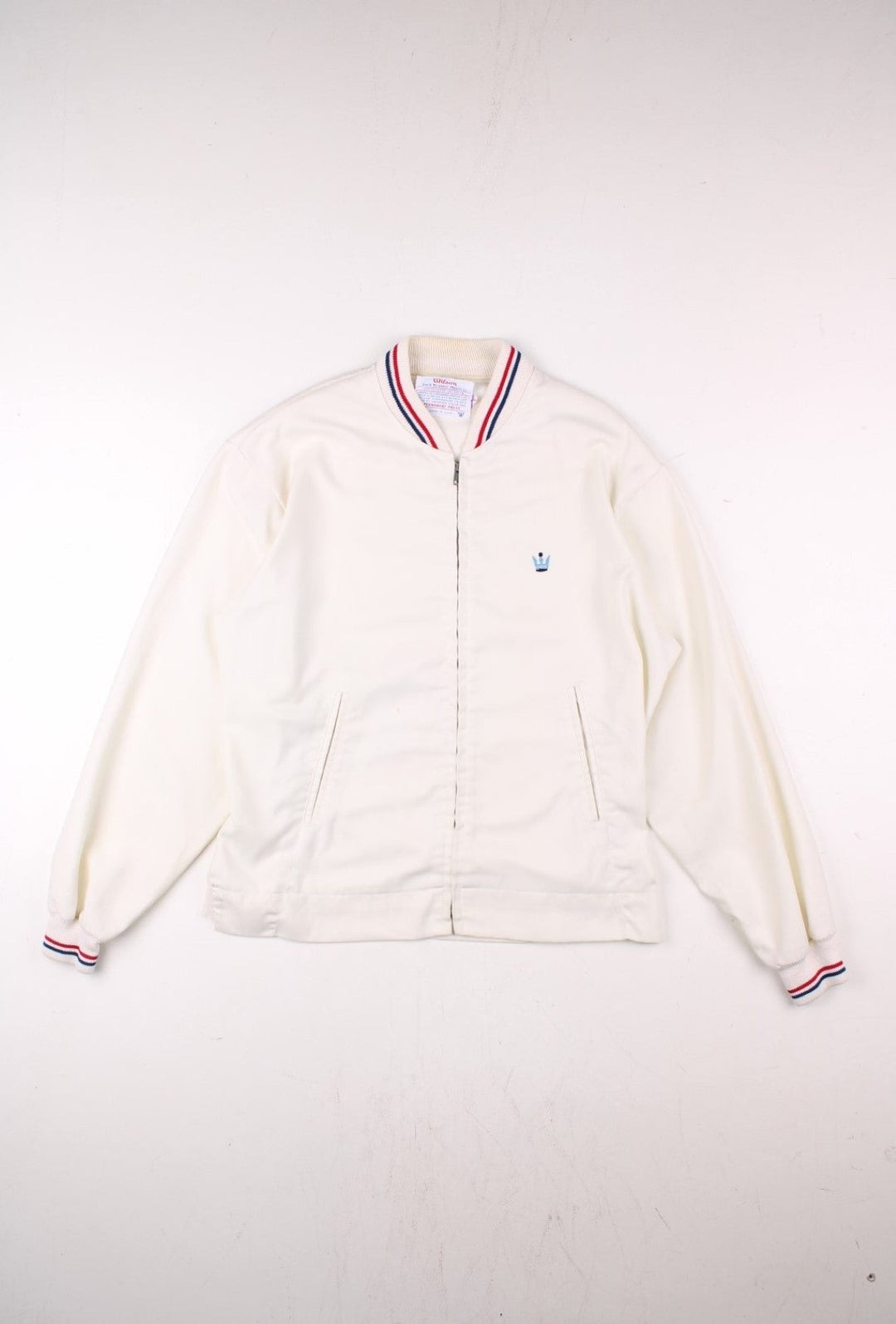 Vintage 1950's Wilson Athletics Jack Kramer made in the USA tennis jacket in white with zip closure, two pockets, red and blue srtipe detailing on the collar and cuffs, and an embroidered crown logo on the chest.