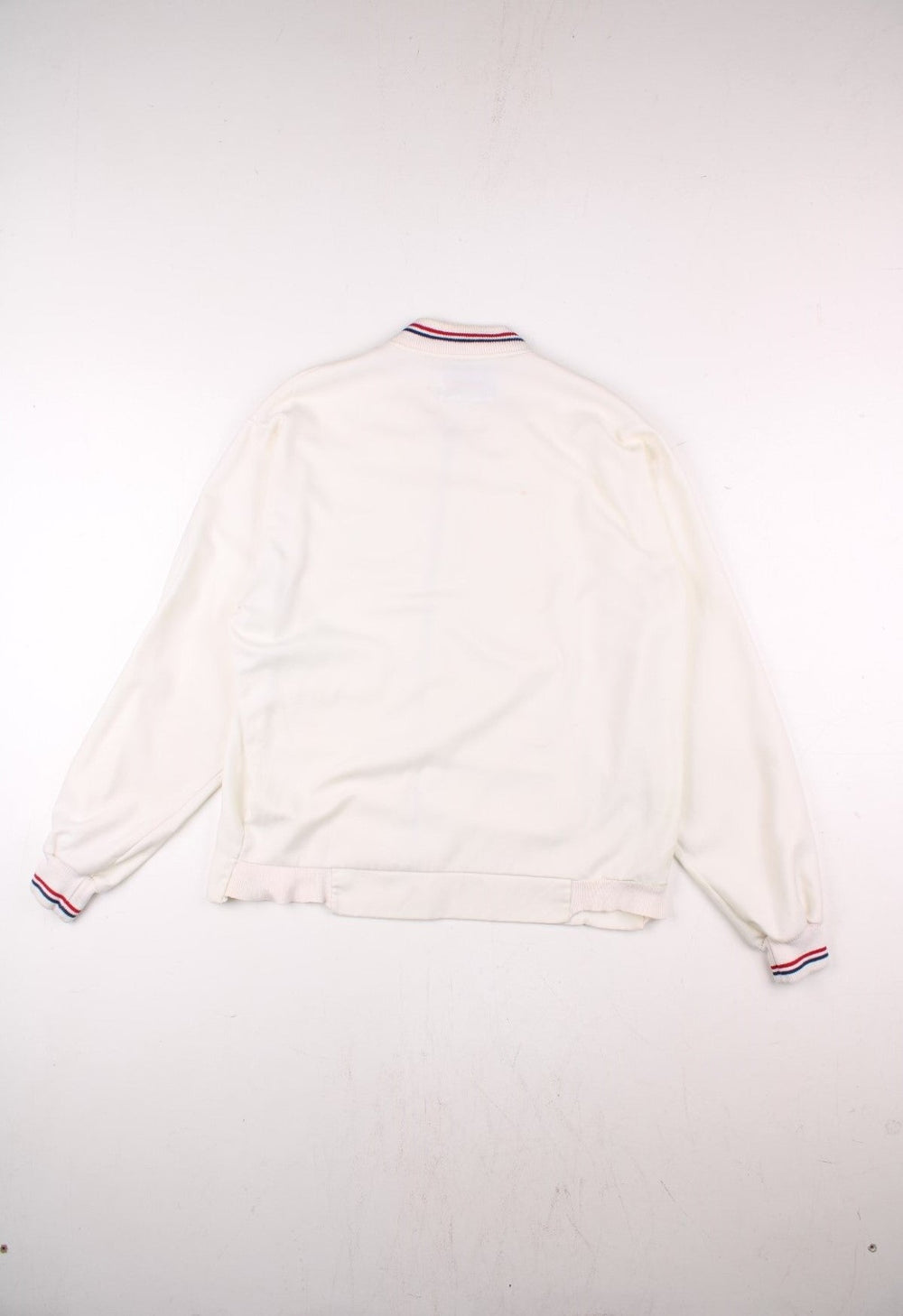 Vintage 1950's Wilson Athletics Jack Kramer made in the USA tennis jacket in white with zip closure, two pockets, red and blue srtipe detailing on the collar and cuffs, and an embroidered crown logo on the chest.