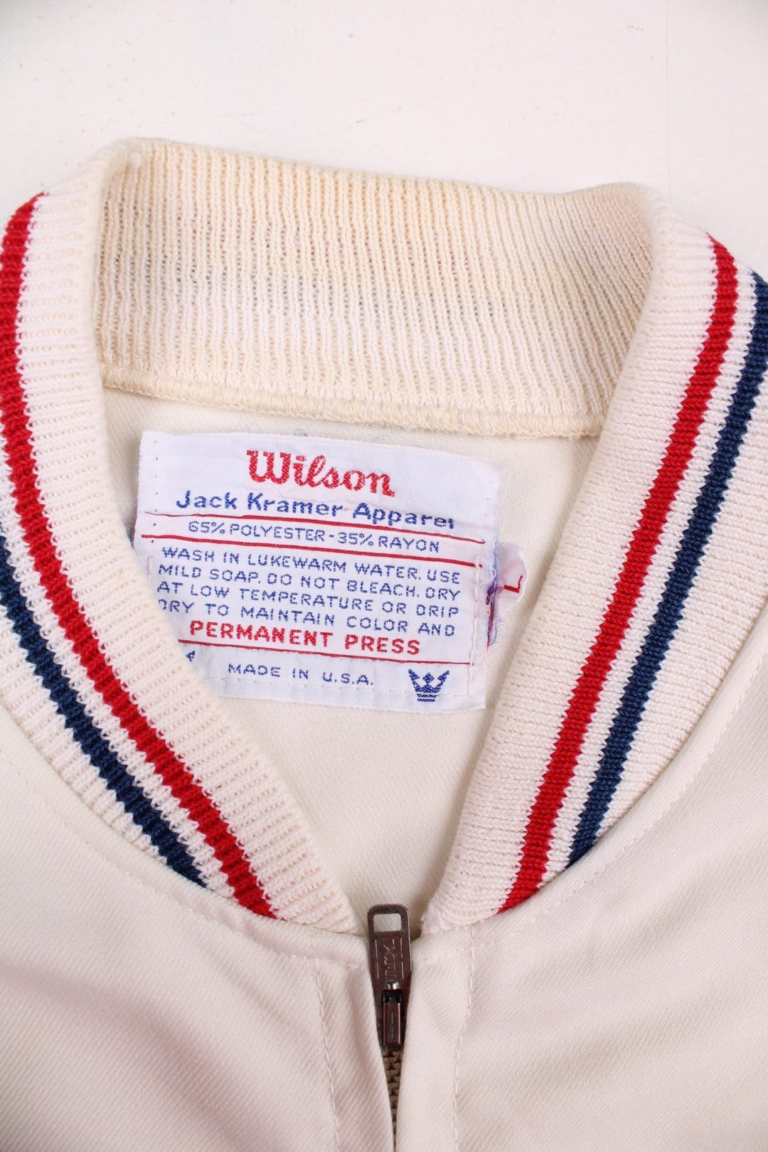 Vintage 1950's Wilson Athletics Jack Kramer made in the USA tennis jacket in white with zip closure, two pockets, red and blue srtipe detailing on the collar and cuffs, and an embroidered crown logo on the chest.