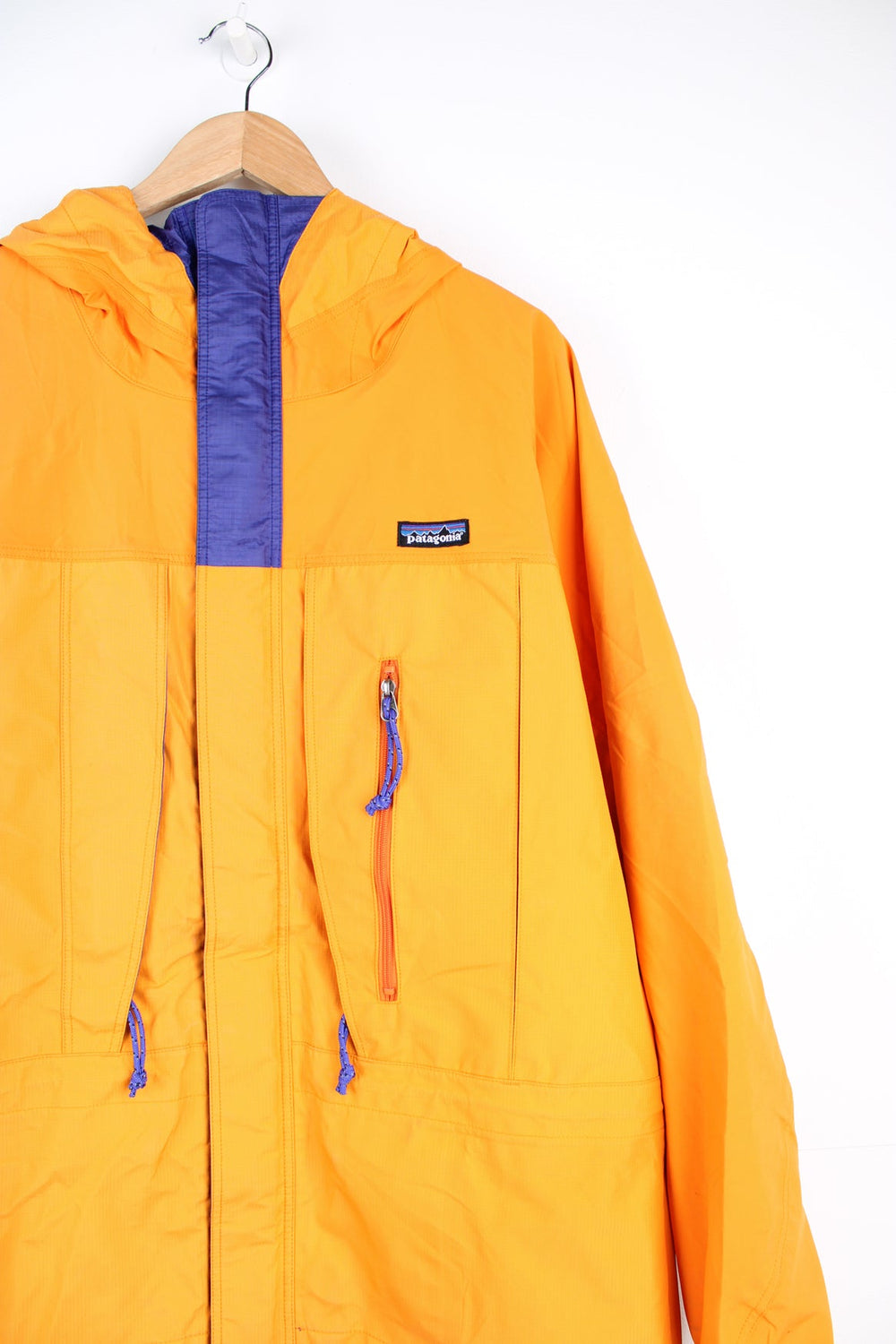 Orange and purple Patagonia hooded rain jacket with embroidered logo on the chest and multiple pockets.